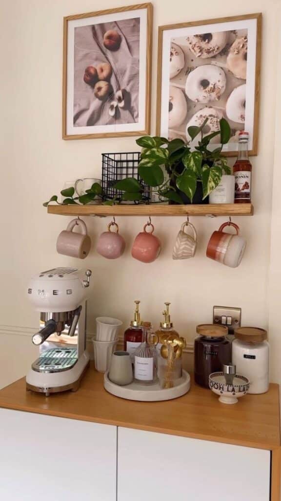 Cozy coffee corner with espresso machine, mugs, plants, and decor on wooden shelves for a stylish kitchen setup.