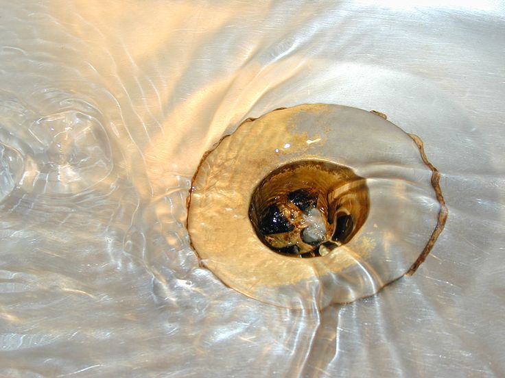 How can I tell if I have a major drain blockage_ Water draining into a metal sink with a visible swirl and reflection. | Sky Rye Design Water draining into a metal sink with a visible swirl and reflection.