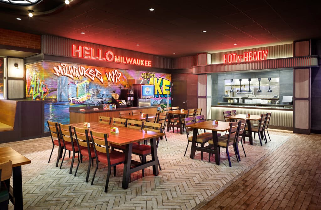 Vibrant Milwaukee restaurant interior with graffiti, neon lights, and wooden tables creates a lively dining atmosphere.