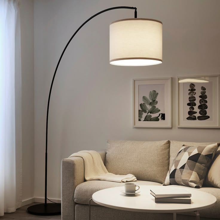 Modern living room with arc floor lamp, cozy beige sofa, geometric cushions, and wall art.