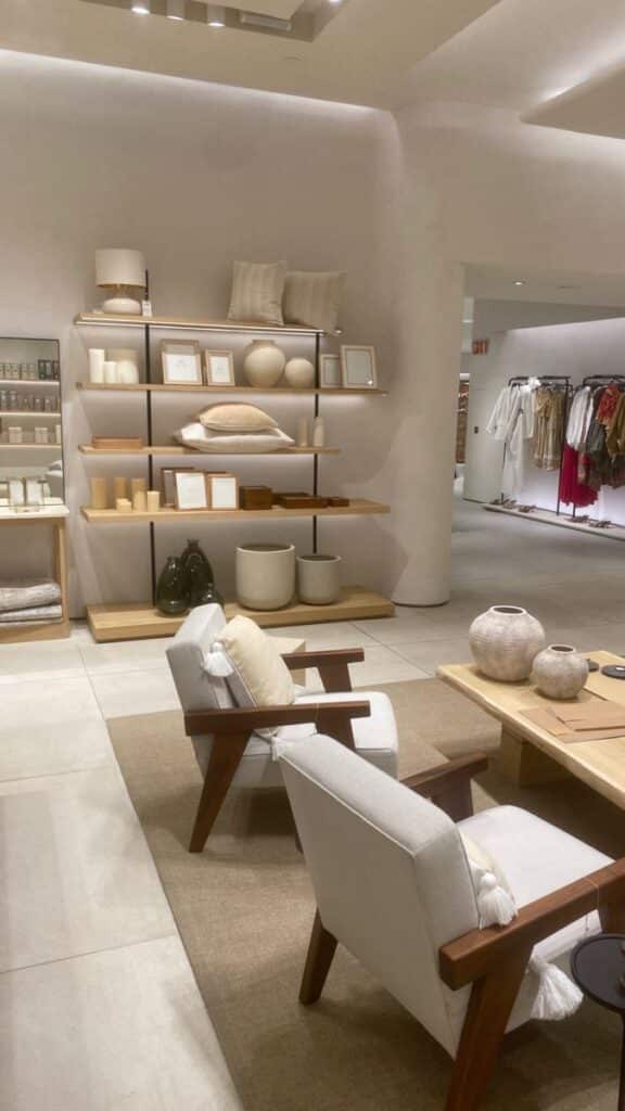 Modern home decor store with neutral tones, stylish shelves, cozy armchairs, and elegant pottery display.