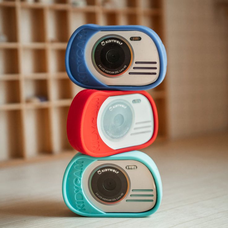 Stack of colorful toy cameras with lens facing forward.