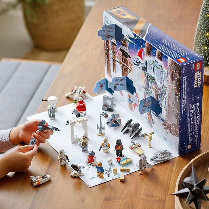 Child playing with a Star Wars LEGO advent calendar set on a wooden table, featuring figurines and mini spaceships.