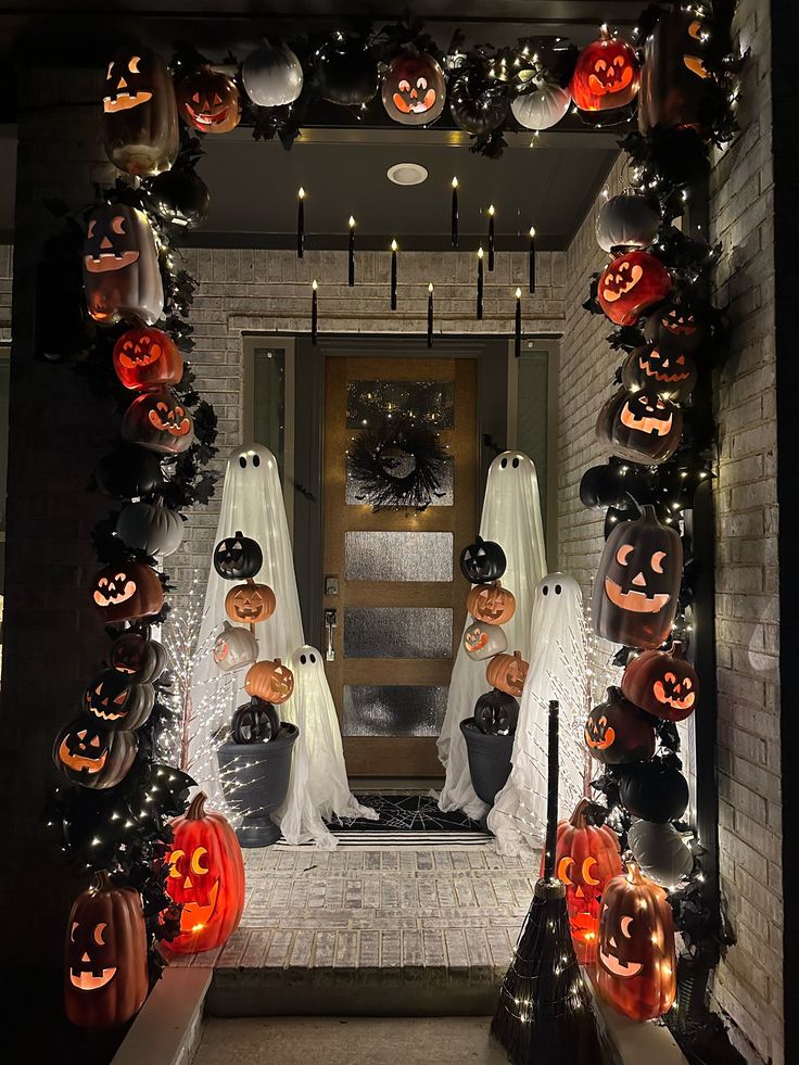 Halloween porch with carved pumpkins, ghost decor, and hanging candles. Spooky and festive entrance display at night.