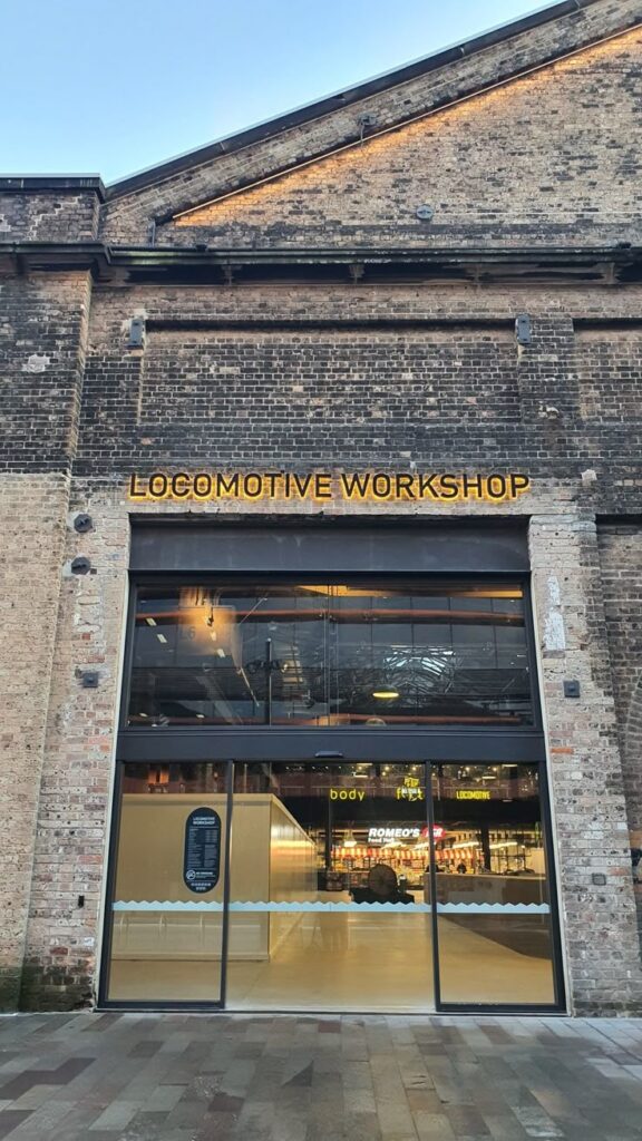 Historic Locomotive Workshop entrance with visible interior shopping and dining area in a renovated industrial building.