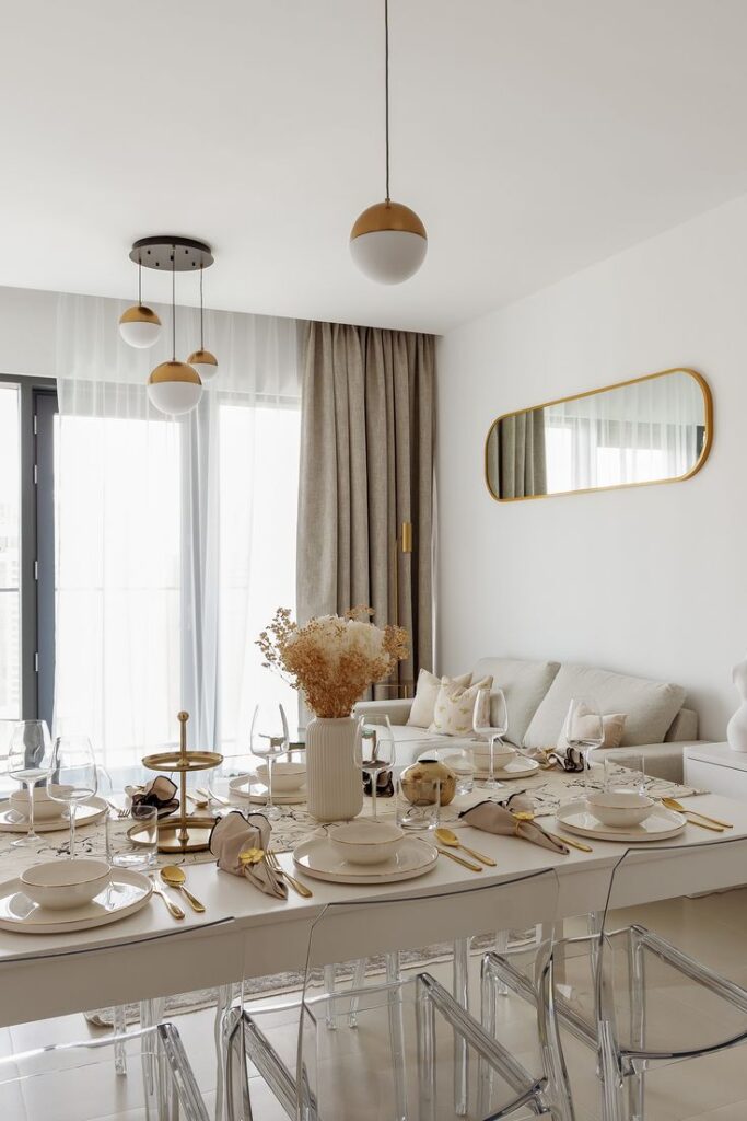 Luxurious yacht-inspired VIDA Dubai Marina apartment Elegant dining room with modern decor, set table, and pendant lights. White and gold accents create a chic ambiance. | Sky Rye Design Elegant dining room with modern decor, set table, and pendant lights. White and gold accents create a chic ambiance.