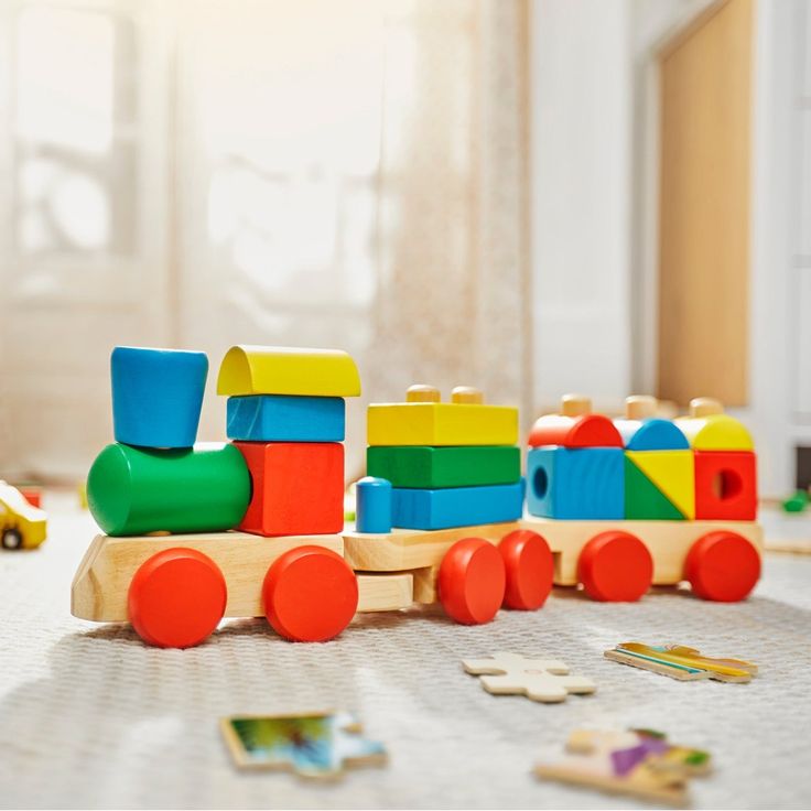 Colorful wooden toy train on carpet with puzzle pieces in cozy, sunlit children's room.