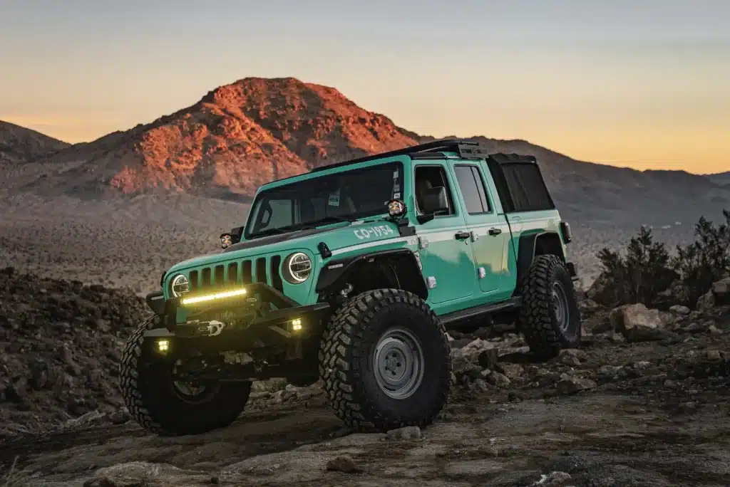 Off-road vehicle on rocky mountain landscape at sunset, showcasing rugged terrain capability.