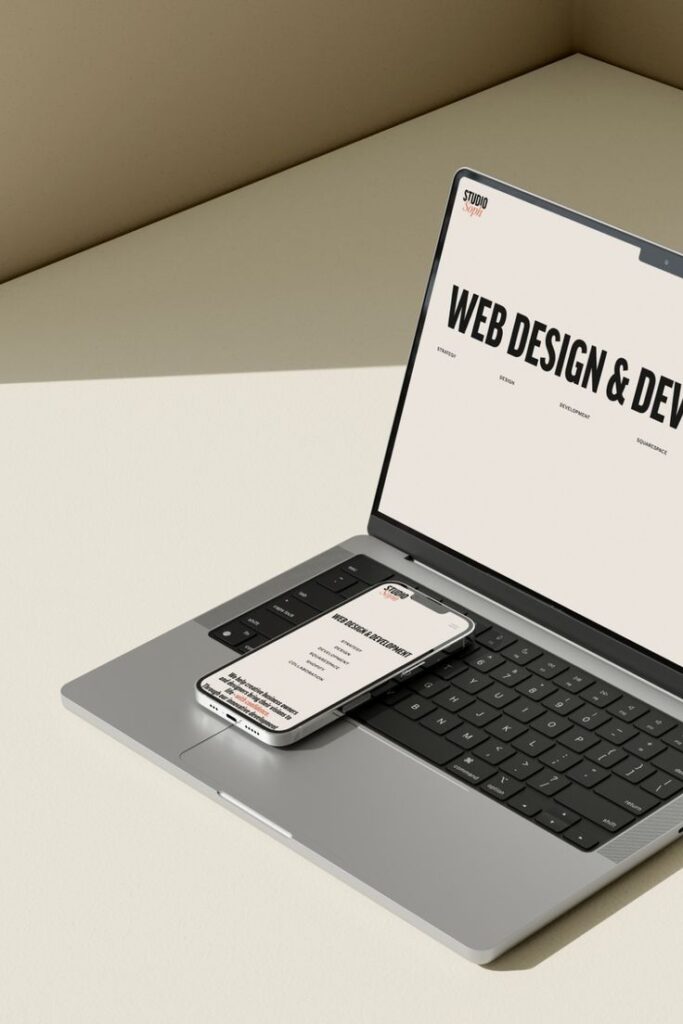 Laptop and smartphone showcasing web design and development services on a minimalist beige background.