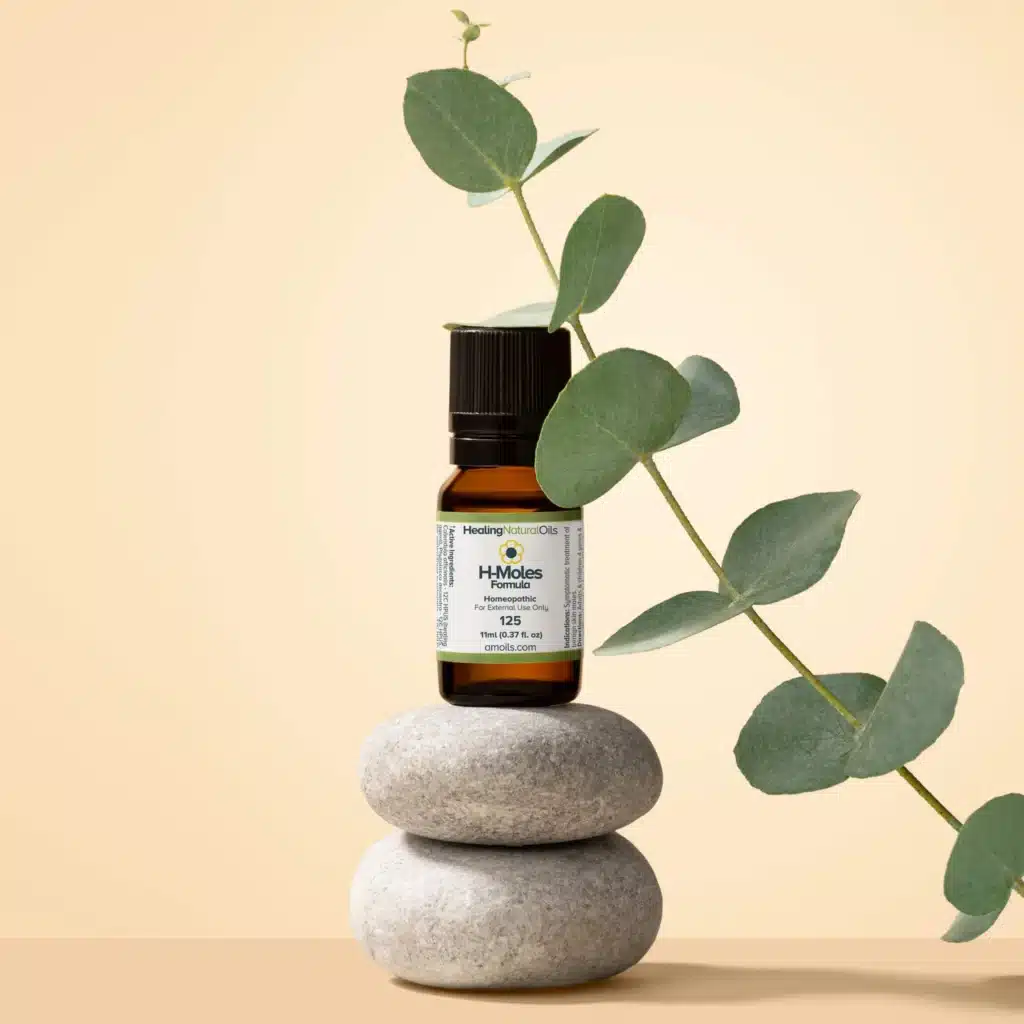 Essential oil bottle on stacked stones with eucalyptus branch, on a beige background. Holistic wellness concept.