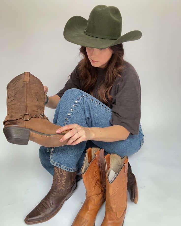 New cowboy boots on the website for all my lil cowgirls out there the real deal or in spirit_ Get them while theyre hot 🤠🔥 Woman in cowboy hat choosing between brown cowboy boots while sitting on floor. Casual fashion choice. | Sky Rye Design Woman in cowboy hat choosing between brown cowboy boots while sitting on floor. Casual fashion choice.