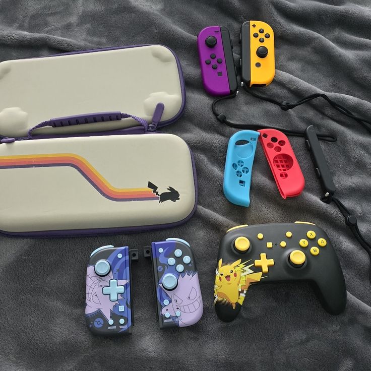 Colorful Nintendo Switch controllers and case featuring Pokémon designs on a soft gray blanket.