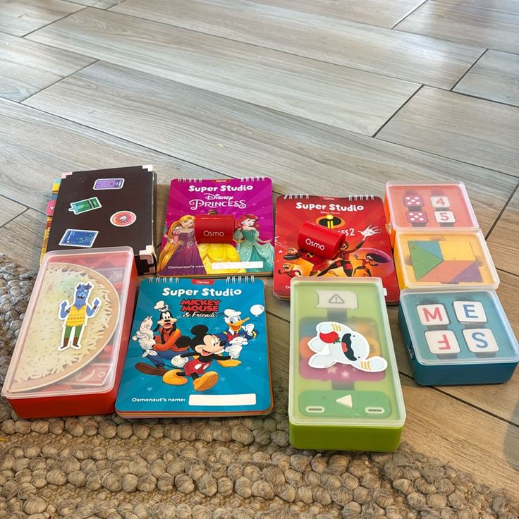 Osmo educational game sets on a wooden floor, featuring Disney Princesses and Mickey Mouse-themed Super Studio kits.