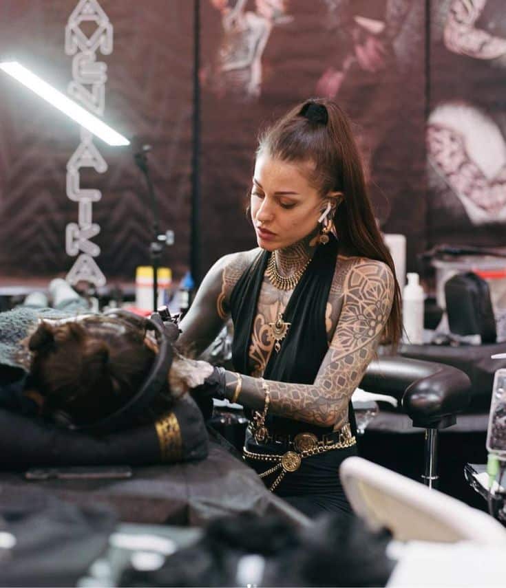 Tattoo artist focused on creating detailed ink design on client's arm in a studio.