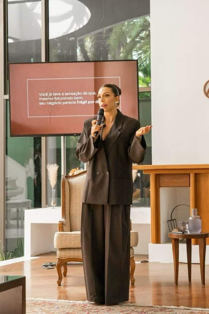 Woman giving a presentation on business stability, holding a microphone in a modern office setting.