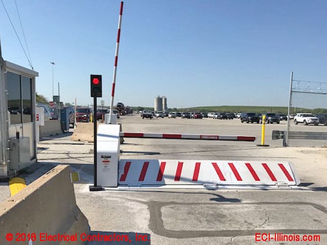 Parking-Wedge-Barrier-Fully-Extended Security gate and traffic barrier at an entrance checkpoint with visible vehicles and industrial background. | Sky Rye Design Security gate and traffic barrier at an entrance checkpoint with visible vehicles and industrial background.