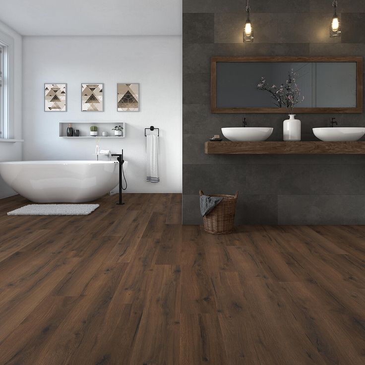 Modern bathroom with wood flooring, freestanding tub, and double sink vanity under warm pendant lights.
