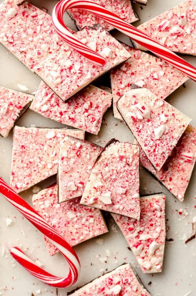 Peppermint bark with candy cane pieces, perfect holiday treat on a beige surface.