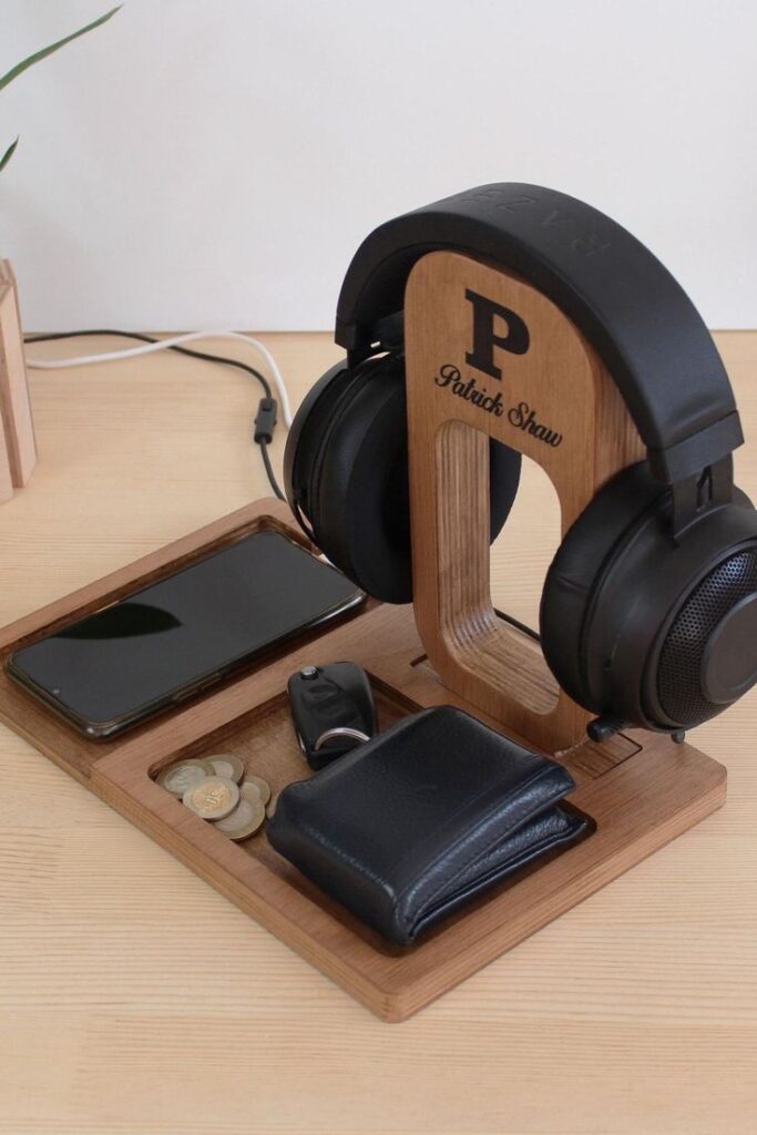 Wooden desk organizer with headphones, phone, wallet, keys, and coins; sleek and organized workspace solution.