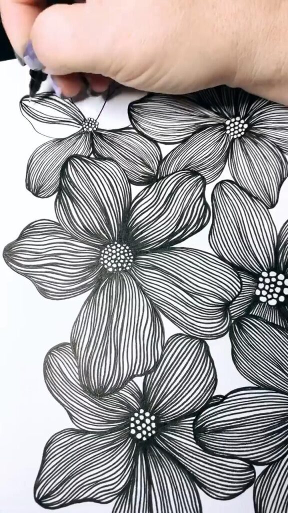Hand drawing intricate black and white floral design with fine lines on paper.