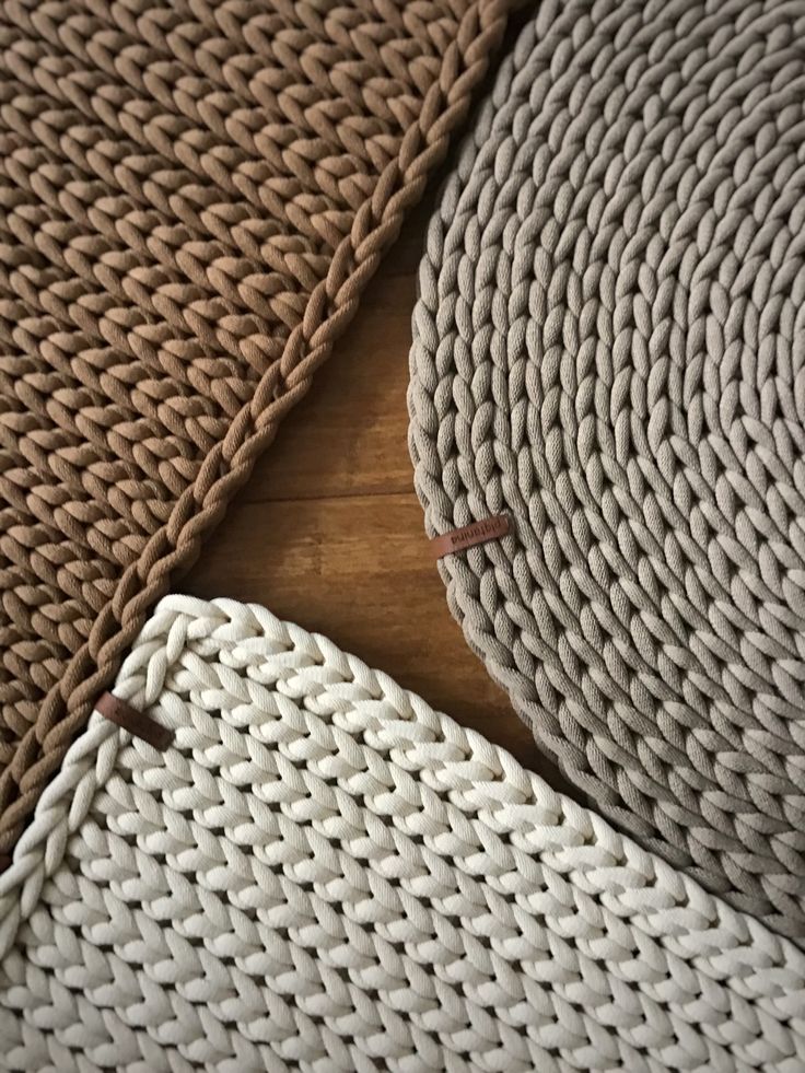 Braided woven placemats in brown, beige, and gray on a wooden surface, showcasing texture and craftsmanship.