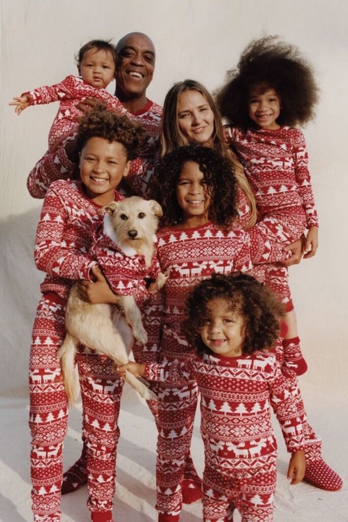 Family in matching red Christmas pajamas posing with a dog, smiling and enjoying festive moments together.