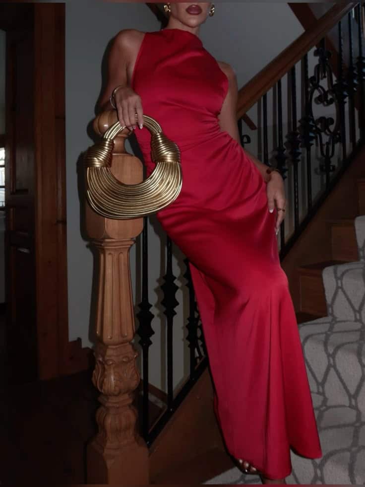 Red gold 💋 Elegantly dressed woman in a red gown holding a unique gold handbag on staircase. | Sky Rye Design Elegantly dressed woman in a red gown holding a unique gold handbag on staircase.