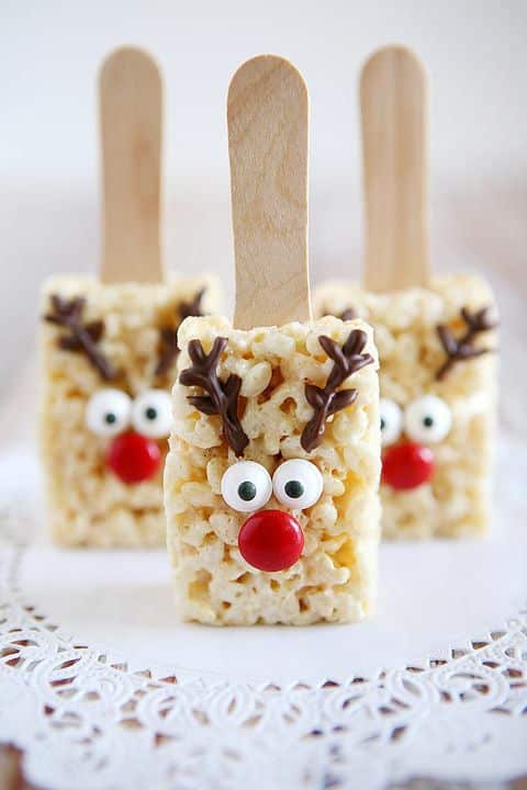 Festive reindeer rice crispy treats on sticks with candy eyes and red noses, perfect for holiday gatherings.