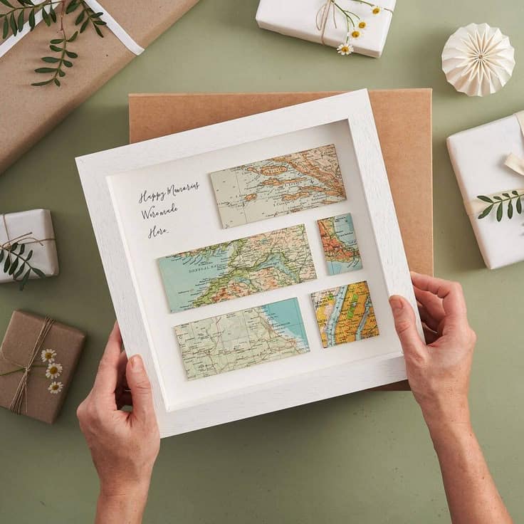 Remember When Personalised Five Map Print Gift By Bombus Framed travel map collage held by hands, surrounded by gift packages on a green background. | Sky Rye Design Framed travel map collage held by hands, surrounded by gift packages on a green background.