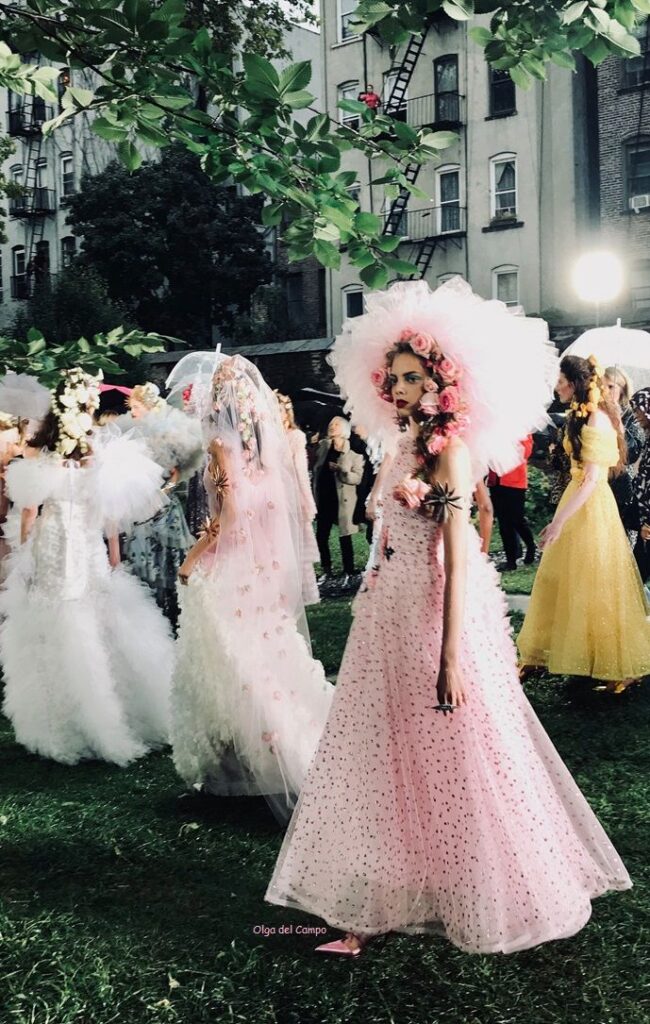 Rodarte SS 2019 Models in elegant, floral gowns at an outdoor fashion event, showcasing unique, vibrant designs. | Sky Rye Design Models in elegant, floral gowns at an outdoor fashion event, showcasing unique, vibrant designs.