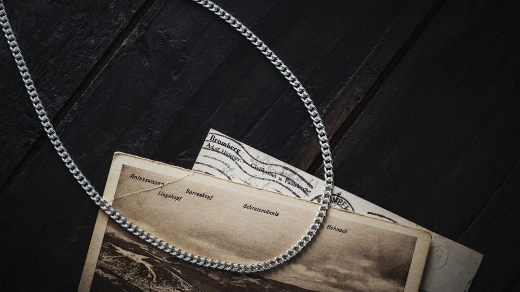 Silver chain with vintage postcards on dark wooden background.