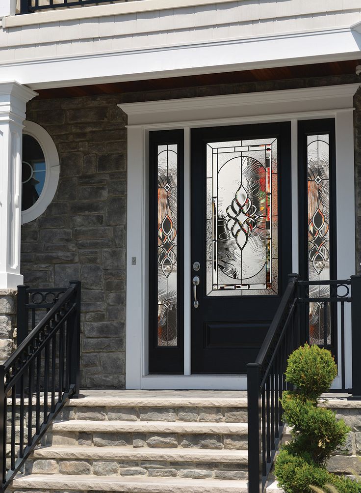 Elegant glass-paneled front door with intricate design, framed by a stone exterior and stairs with black railings.