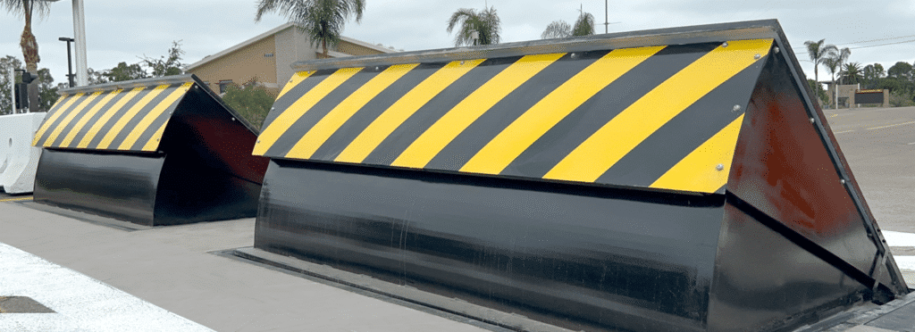 Sloan-Security-Group-Delta-Wedge-Barrier-Miramar Heavy-duty vehicle barriers with yellow and black stripes for road safety and traffic control. | Sky Rye Design Heavy-duty vehicle barriers with yellow and black stripes for road safety and traffic control.