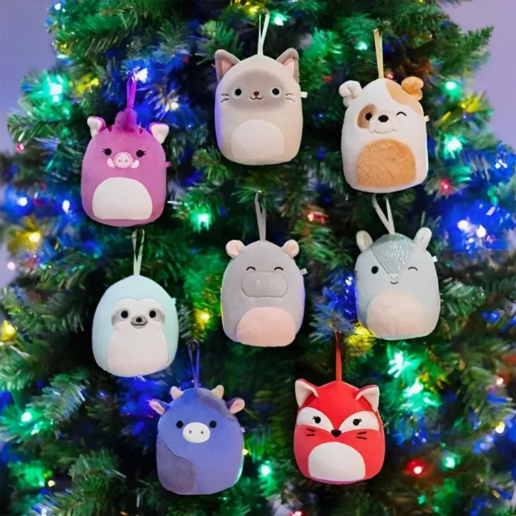 Cute plush animal ornaments hanging on a Christmas tree with colorful lights.