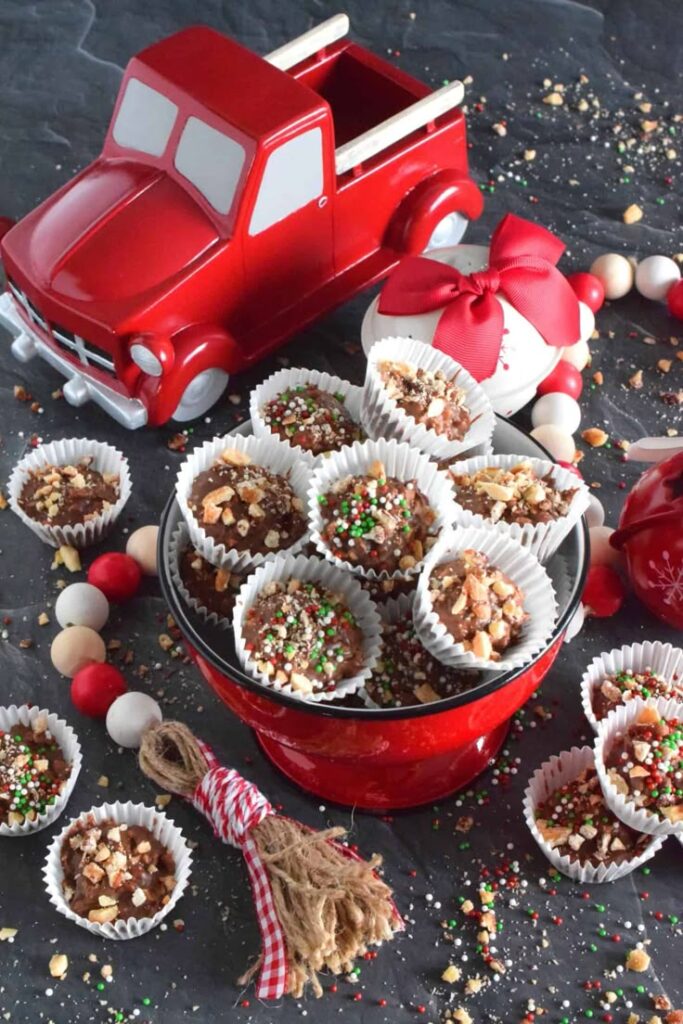 Festive holiday treats with sprinkles and nuts in cups beside a decorative red truck and ornaments.