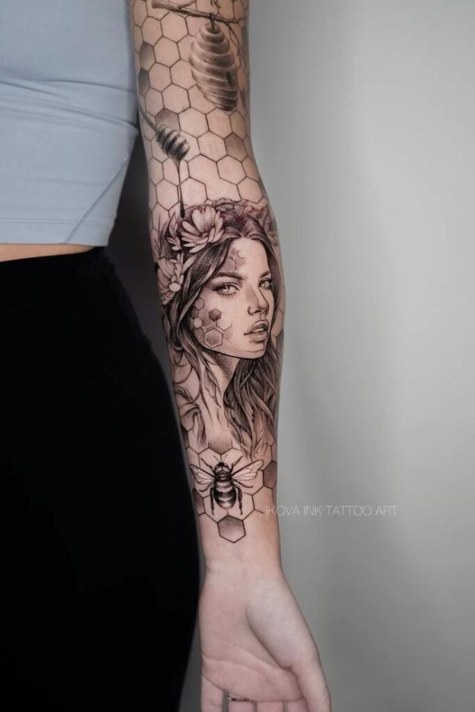 Detailed forearm tattoo of woman's face with honeycomb and bee design.