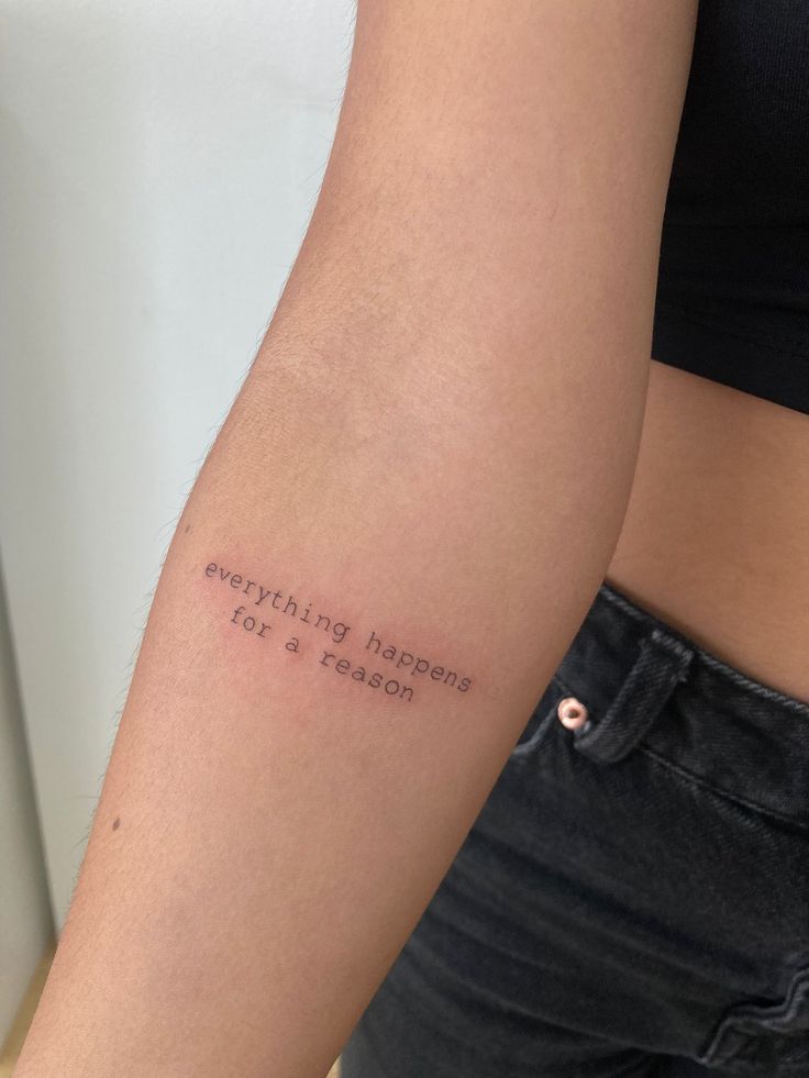 Forearm tattoo with the text “everything happens for a reason,” inked in black on a person's arm.