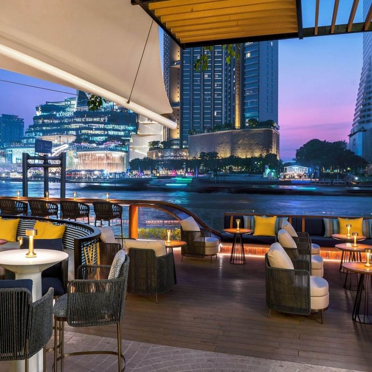 Riverside lounge with elegant seating and city skyline at sunset, perfect for relaxation and enjoying evening views.