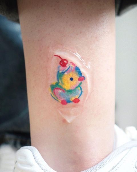 Colorful abstract balloon dog tattoo on leg under protective film.
