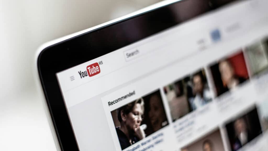 Close-up of a computer screen displaying YouTube homepage, showing recommended video thumbnails.