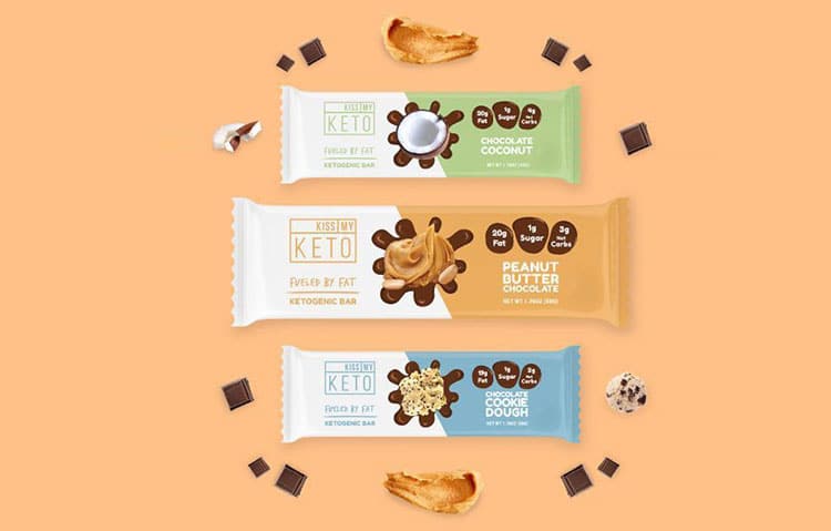 Versatility Keto bars assortment: Chocolate Coconut, Peanut Butter Chocolate, Cookie Dough flavors with ingredients on orange background. | Sky Rye Design Keto bars assortment: Chocolate Coconut, Peanut Butter Chocolate, Cookie Dough flavors with ingredients on orange background.