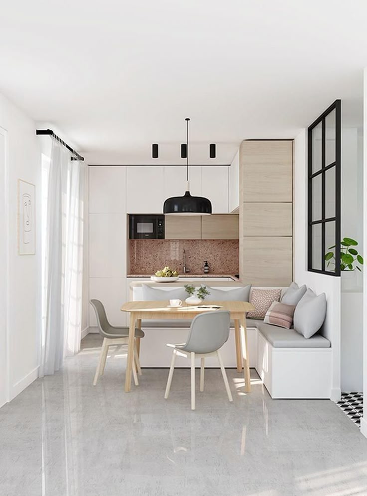 Modern kitchen with beige cabinets, dining table, gray chairs, built-in bench, and black pendant light.