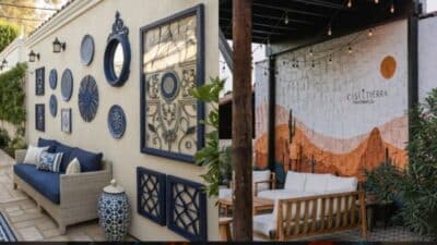 Outdoor patio with blue wall art and cozy seating, featuring a mural and string lights for an inviting atmosphere.