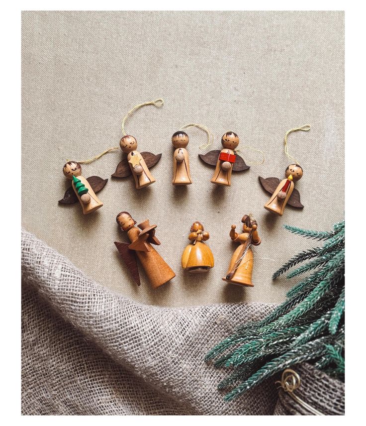 Vintage Erzgebirge Christmas Ornaments_ German Wooden Angels Set of 8 Wooden Christmas ornaments with angels and figures on burlap, accented by evergreen branches. | Sky Rye Design Wooden Christmas ornaments with angels and figures on burlap, accented by evergreen branches.