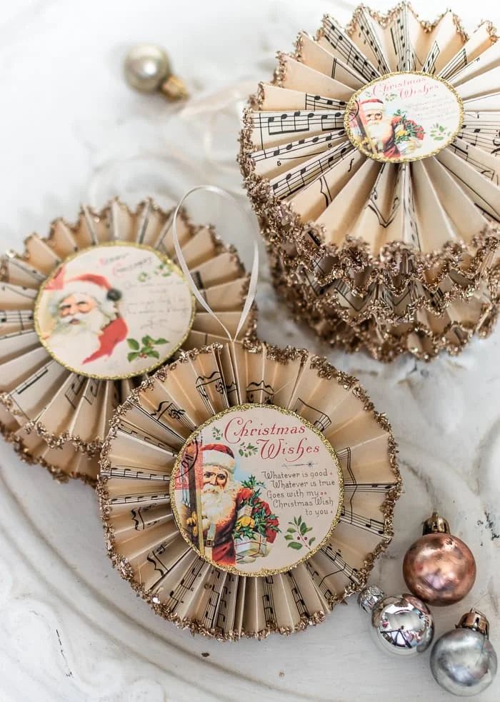 Vintage Christmas ornaments made from sheet music with Santa images and festive decorations.