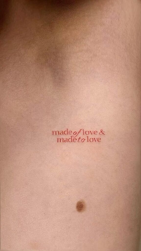 Minimalist tattoo with the phrase made of love & made to love on skin background.