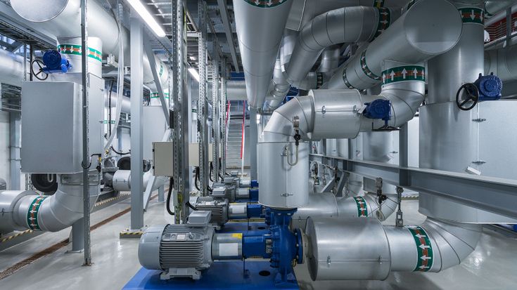 Industrial facility with large metal pipes, valves, and machinery in a modern processing plant.