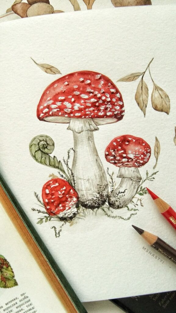 Watercolor illustration of red mushrooms with white spots surrounded by leaves and art supplies.