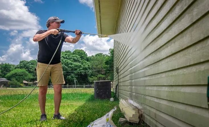 What PSI Pressure Washer for House Siding_ Guide and Tips Man pressure washing house siding on a sunny day for exterior cleaning. | Sky Rye Design Man pressure washing house siding on a sunny day for exterior cleaning.