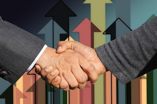 Handshake in front of upward arrows, symbolizing business growth and partnership success.